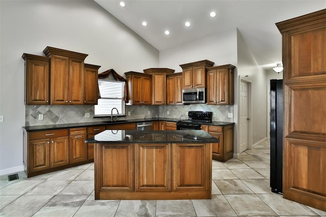 kitchen featuring sink, light tile patterned floors, black appliances, a kitchen island, and dark stone counters