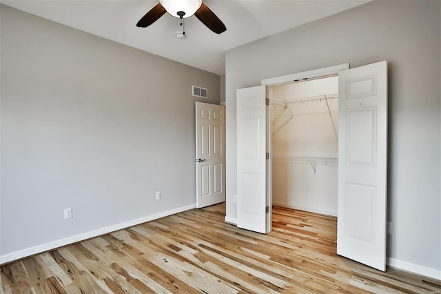 unfurnished bedroom featuring ceiling fan, a spacious closet, light hardwood / wood-style floors, and a closet