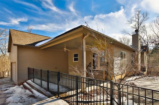 snow covered property with a garage and ceiling fan