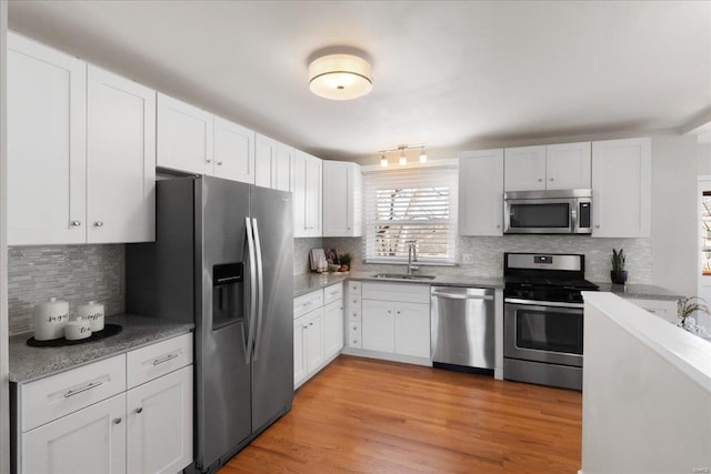 kitchen with appliances with stainless steel finishes, sink, light hardwood / wood-style flooring, and white cabinets