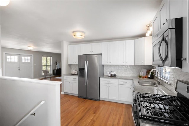 kitchen featuring stainless steel appliances, sink, light hardwood / wood-style flooring, and white cabinets