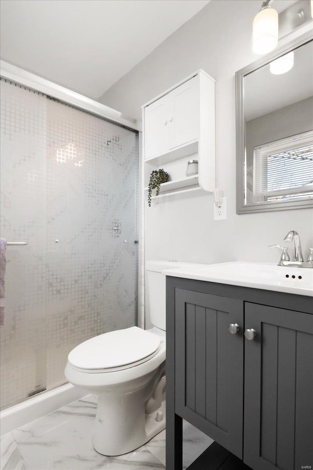 bathroom featuring vanity, a shower with shower door, and toilet