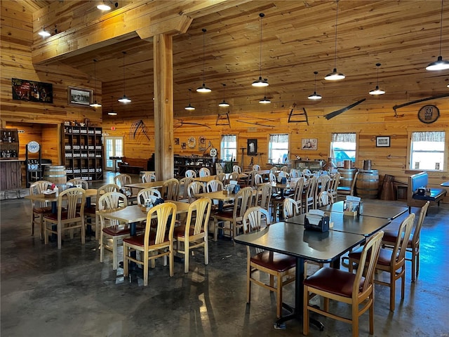 dining space featuring high vaulted ceiling and wood walls