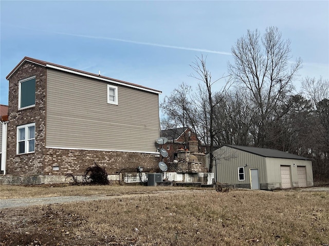 view of home's exterior featuring an outbuilding, a garage, a yard, and central AC