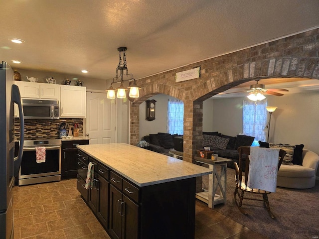 kitchen featuring a kitchen island, pendant lighting, white cabinetry, decorative backsplash, and stainless steel appliances