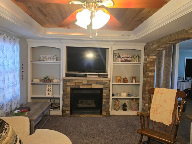 carpeted living room with wood ceiling, a tray ceiling, a fireplace, ornamental molding, and built in shelves