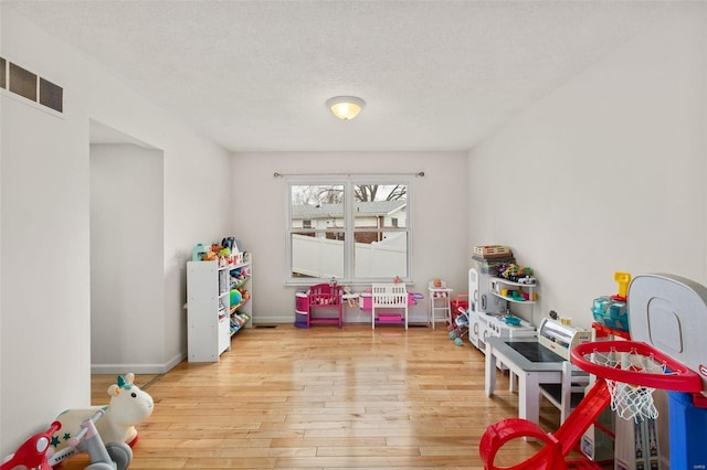 game room with light hardwood / wood-style flooring and a textured ceiling