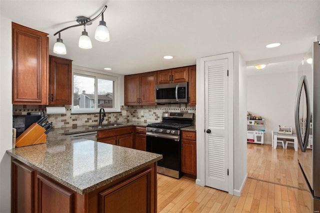 kitchen with sink, stainless steel appliances, light hardwood / wood-style floors, decorative backsplash, and dark stone counters