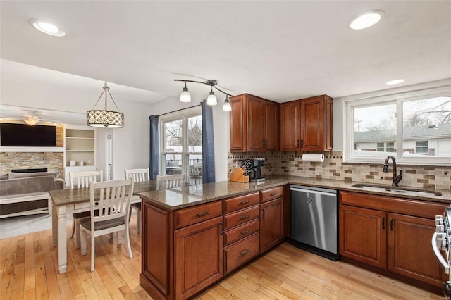 kitchen with appliances with stainless steel finishes, pendant lighting, sink, dark stone countertops, and kitchen peninsula