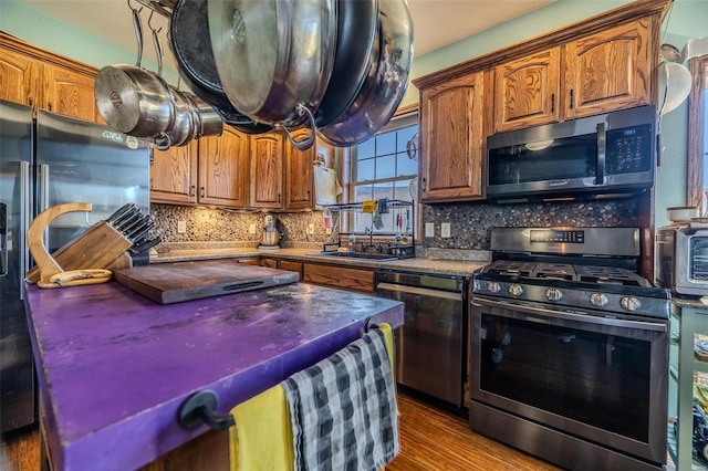 kitchen with stainless steel appliances, sink, hardwood / wood-style floors, and backsplash