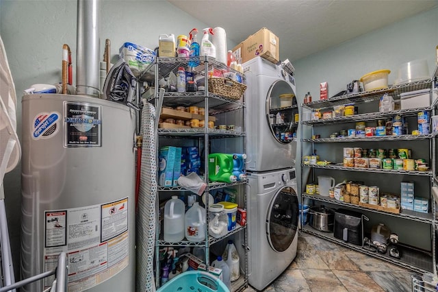 clothes washing area featuring water heater and stacked washer / drying machine