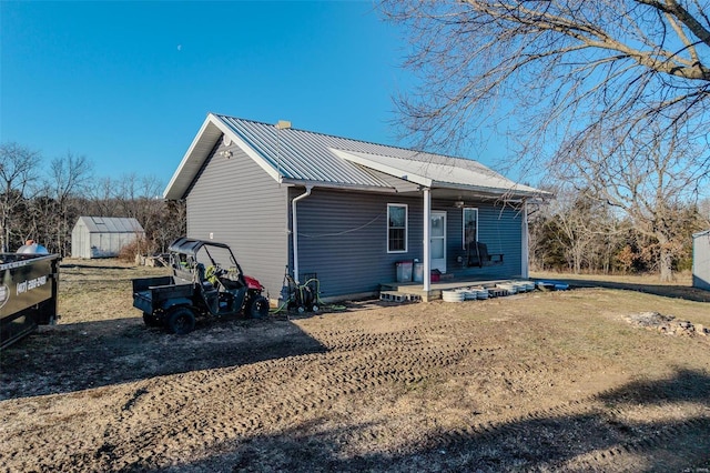 rear view of house with a shed, a yard, and a porch