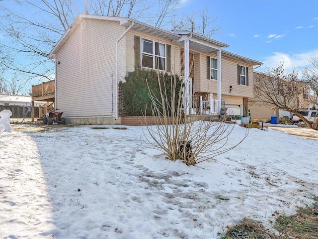 snow covered back of property with a garage