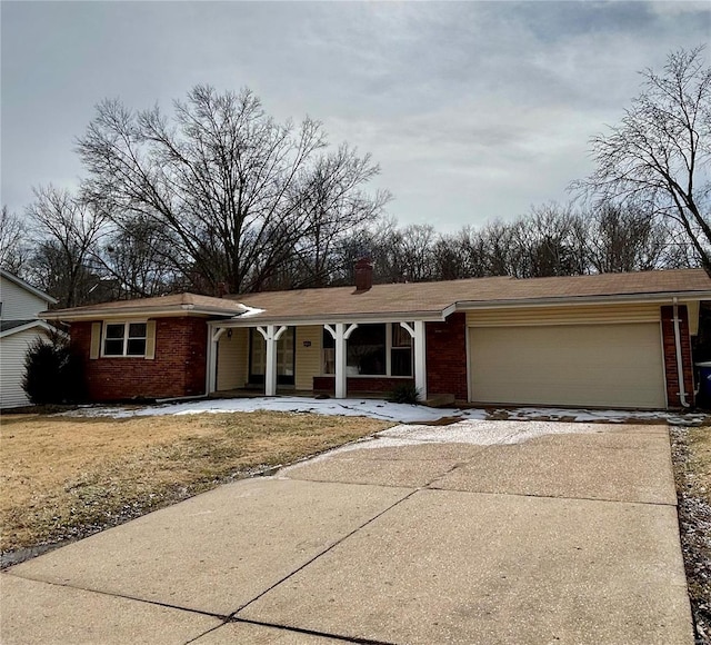 view of front of house featuring a garage, driveway, brick siding, and a chimney