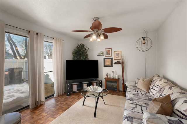 living room featuring ceiling fan, dark parquet floors, and a textured ceiling