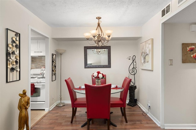 dining room with a chandelier, hardwood / wood-style floors, and a textured ceiling