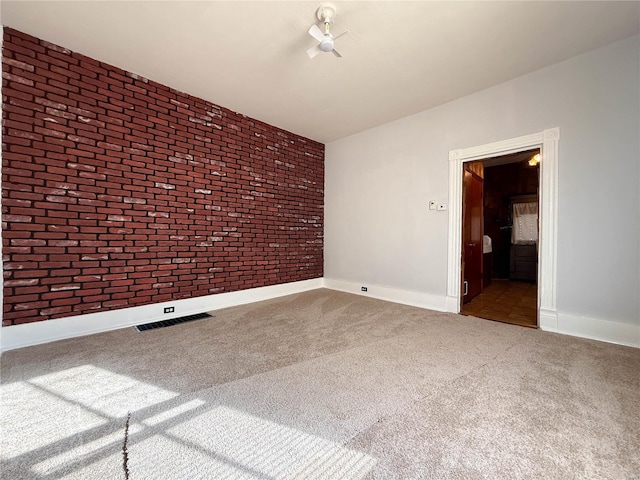 carpeted empty room featuring brick wall