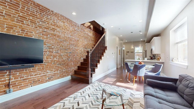 living room with hardwood / wood-style flooring and brick wall