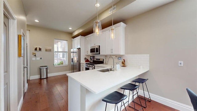 kitchen with stainless steel appliances, white cabinets, a kitchen bar, decorative light fixtures, and kitchen peninsula