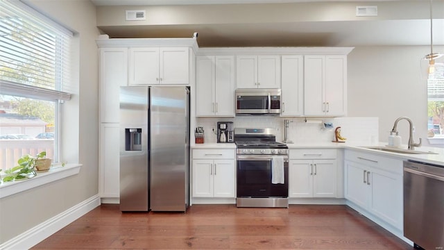 kitchen with appliances with stainless steel finishes, tasteful backsplash, white cabinetry, sink, and dark hardwood / wood-style flooring