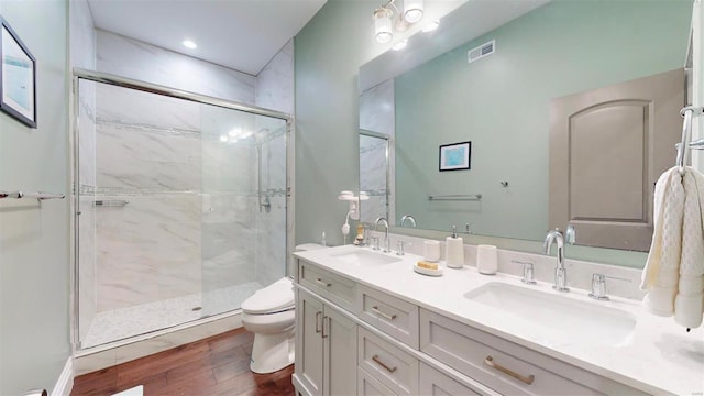 bathroom featuring vanity, hardwood / wood-style flooring, a shower with door, and toilet