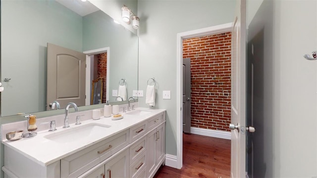 bathroom featuring vanity, brick wall, and hardwood / wood-style floors