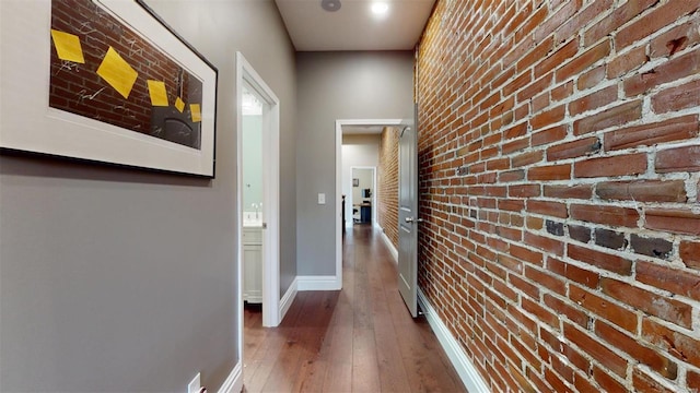 hall with dark hardwood / wood-style flooring and brick wall