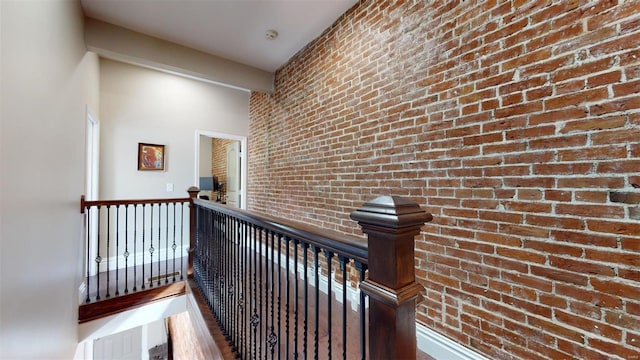 corridor featuring hardwood / wood-style flooring and brick wall