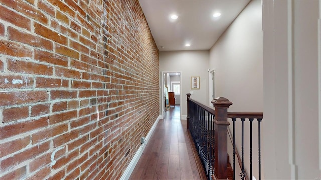 corridor with dark hardwood / wood-style flooring and brick wall