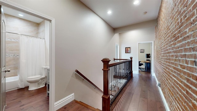 hallway featuring brick wall and dark hardwood / wood-style floors