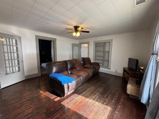 living room with built in shelves, ceiling fan, and dark hardwood / wood-style flooring