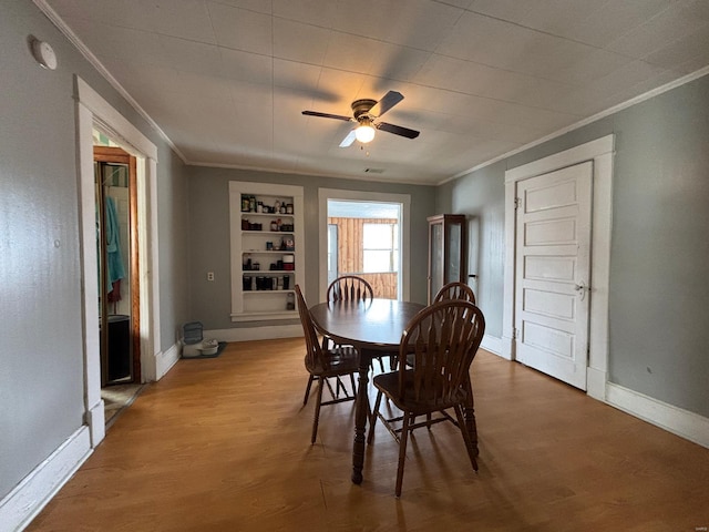 dining area featuring crown molding, hardwood / wood-style floors, built in shelves, and ceiling fan