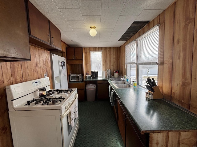 kitchen with sink, white appliances, and wood walls