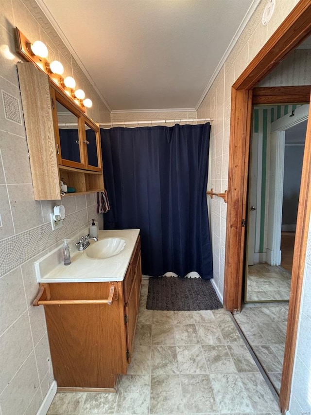 bathroom with a shower with curtain, ornamental molding, vanity, and tile walls