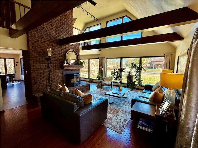 living room with high vaulted ceiling, a brick fireplace, track lighting, dark hardwood / wood-style flooring, and beam ceiling