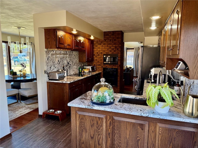 kitchen featuring dark hardwood / wood-style floors, kitchen peninsula, light stone countertops, decorative backsplash, and black appliances