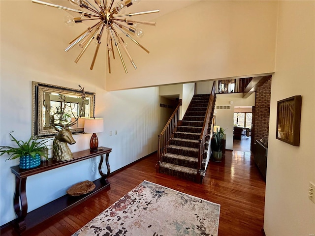 stairway with hardwood / wood-style floors, a high ceiling, and a notable chandelier