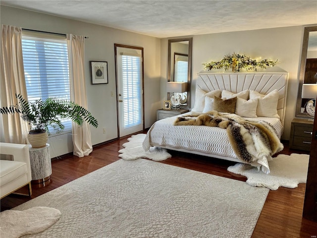 bedroom with access to exterior, dark wood-type flooring, and a textured ceiling