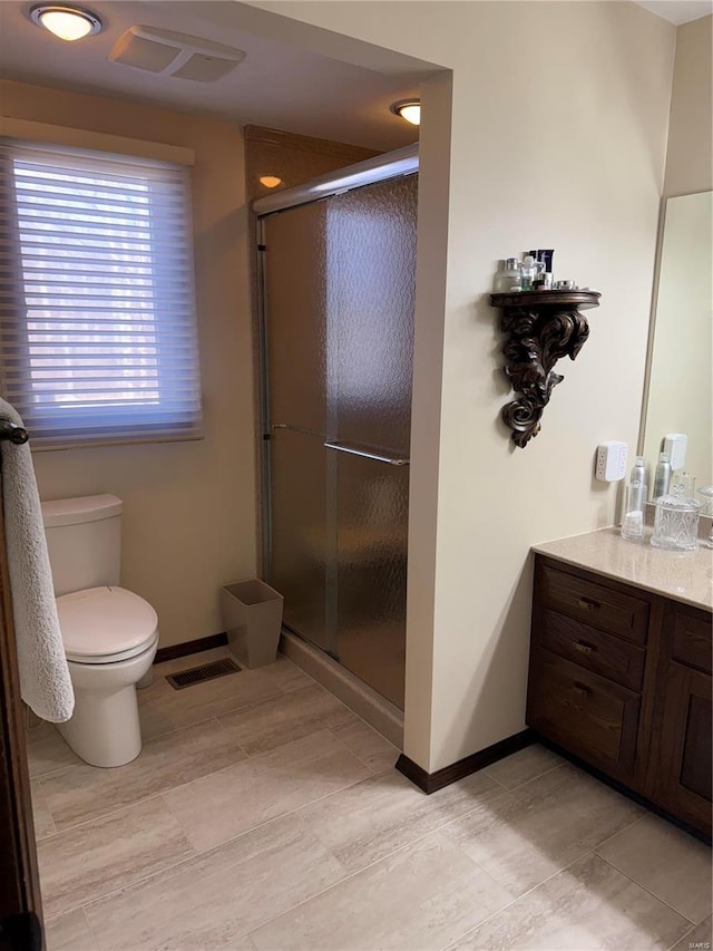 bathroom with vanity, a shower with door, and toilet