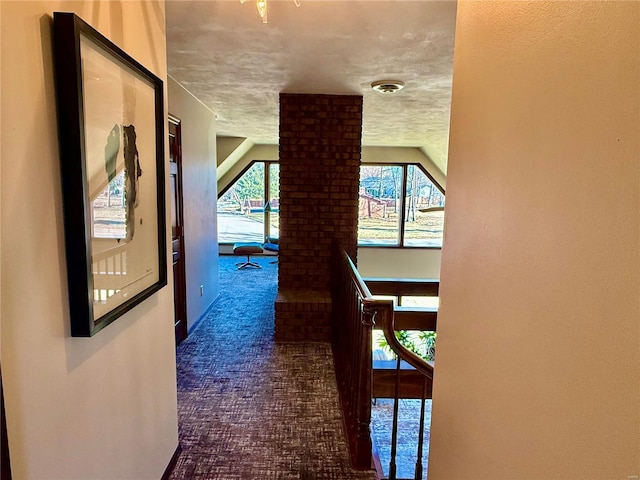 corridor with dark colored carpet and a textured ceiling