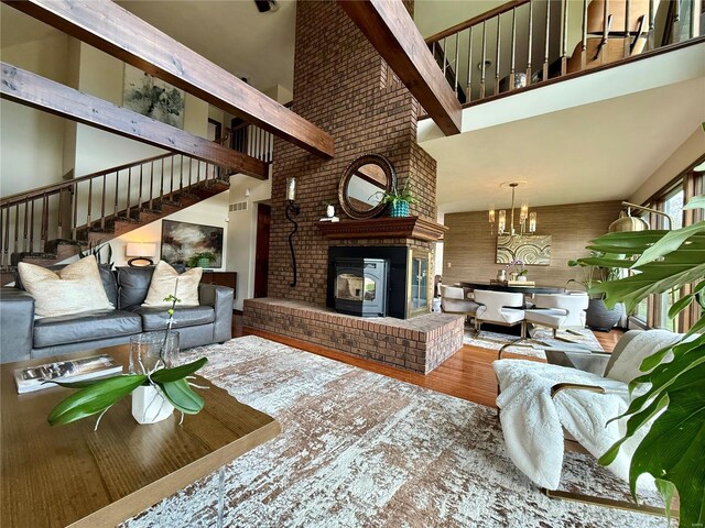 living room featuring visible vents, an inviting chandelier, stairway, wood finished floors, and a towering ceiling
