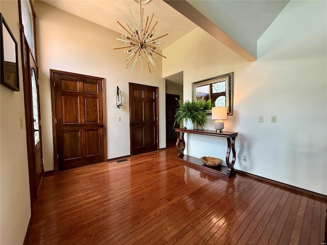 entryway featuring a chandelier, wood-type flooring, high vaulted ceiling, and baseboards
