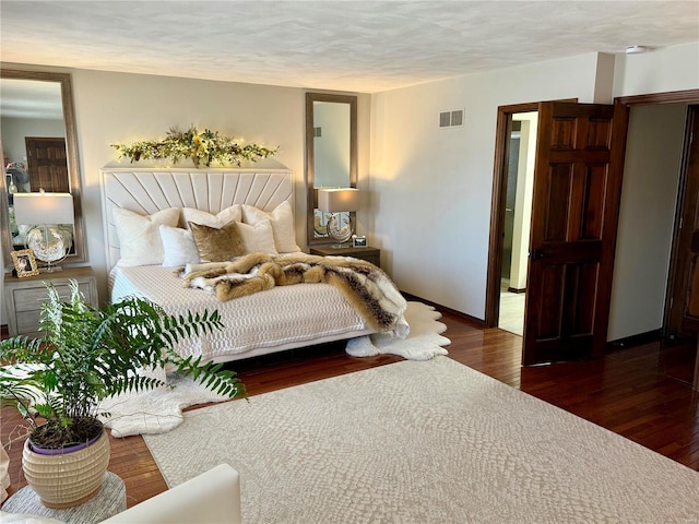 bedroom featuring a textured ceiling, wood finished floors, baseboards, and visible vents