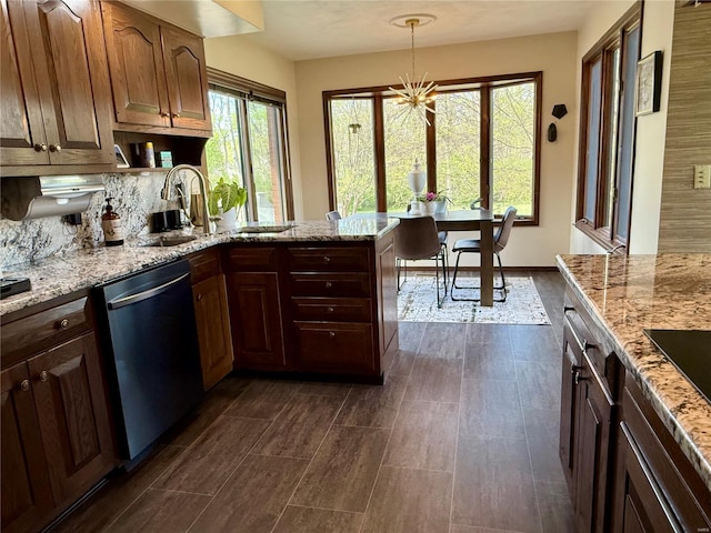 kitchen with stainless steel dishwasher, light stone countertops, and a sink