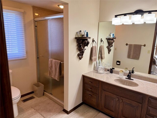 full bath featuring toilet, a stall shower, vanity, and visible vents
