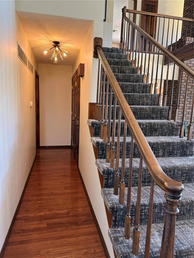 stairs featuring ceiling fan, visible vents, baseboards, and wood finished floors