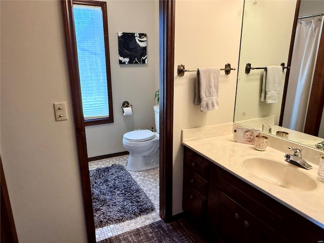 full bathroom with toilet, vanity, and baseboards