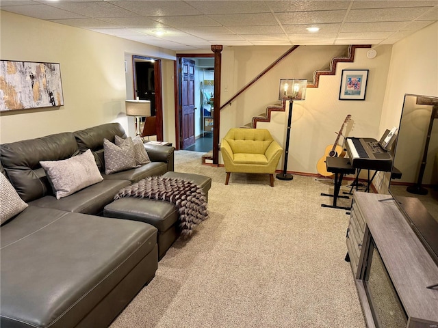 living room with stairs, a drop ceiling, baseboards, and carpet floors