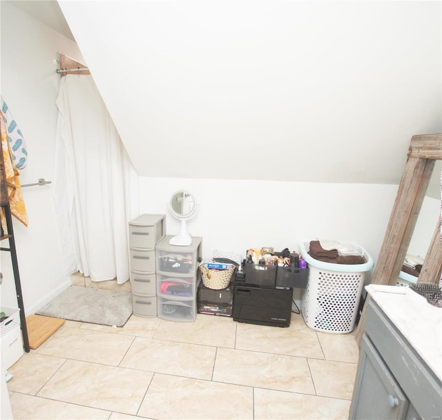 bathroom featuring tile patterned flooring, vanity, and lofted ceiling