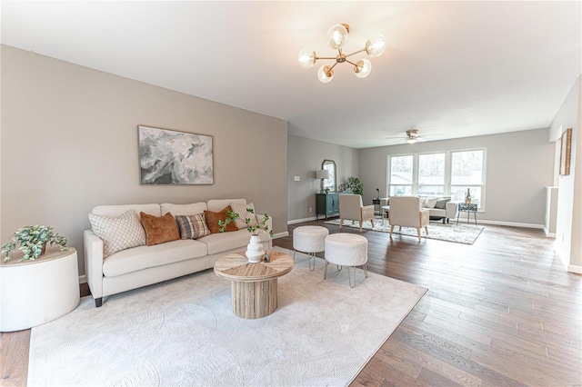 living room with ceiling fan with notable chandelier and light hardwood / wood-style floors